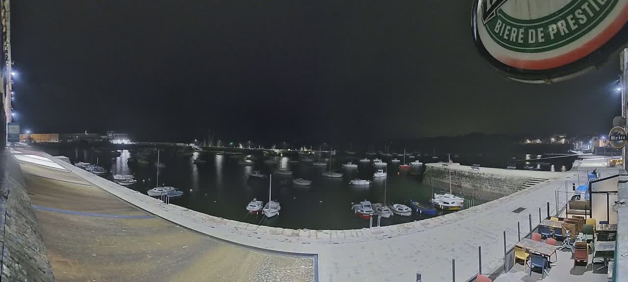 A nighttime view of a harbor filled with boats, under a dark sky.