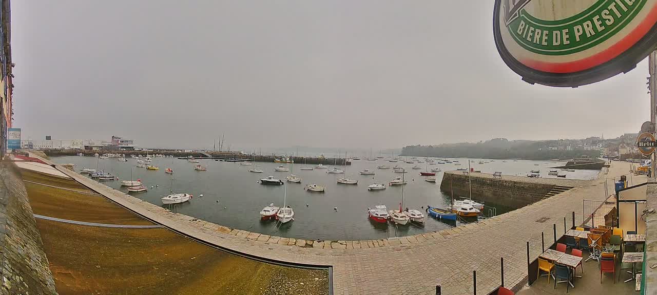 Numerous small boats are moored in a harbor on an overcast day.
