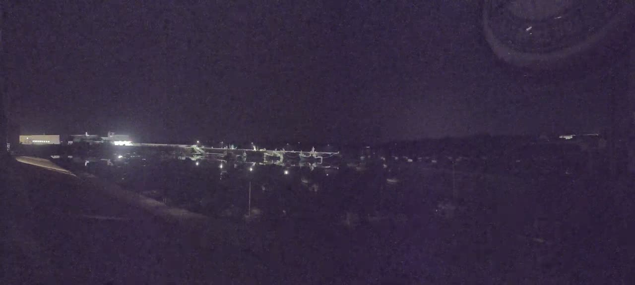 A nighttime, low-light view of a harbor filled with boats, with a building illuminated in the distance.