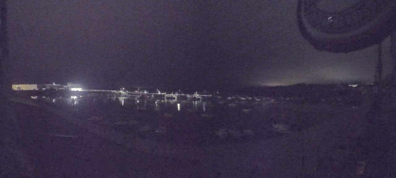 A nighttime view of a harbor filled with boats under a dark, cloudy sky.