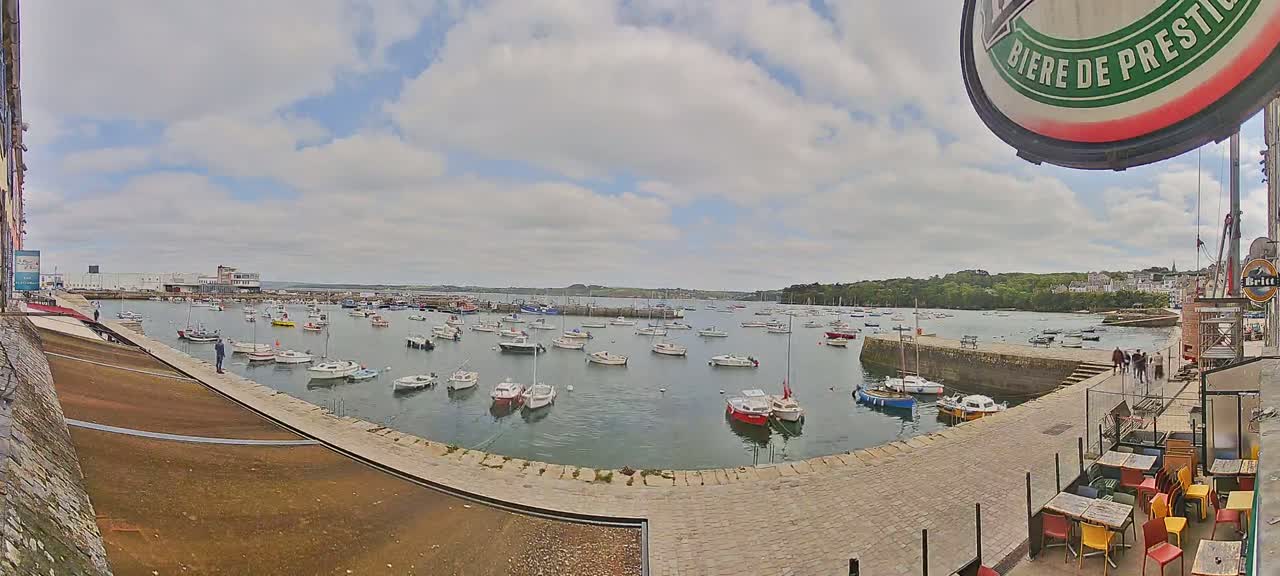 A harbor filled with numerous boats under a partly cloudy sky.