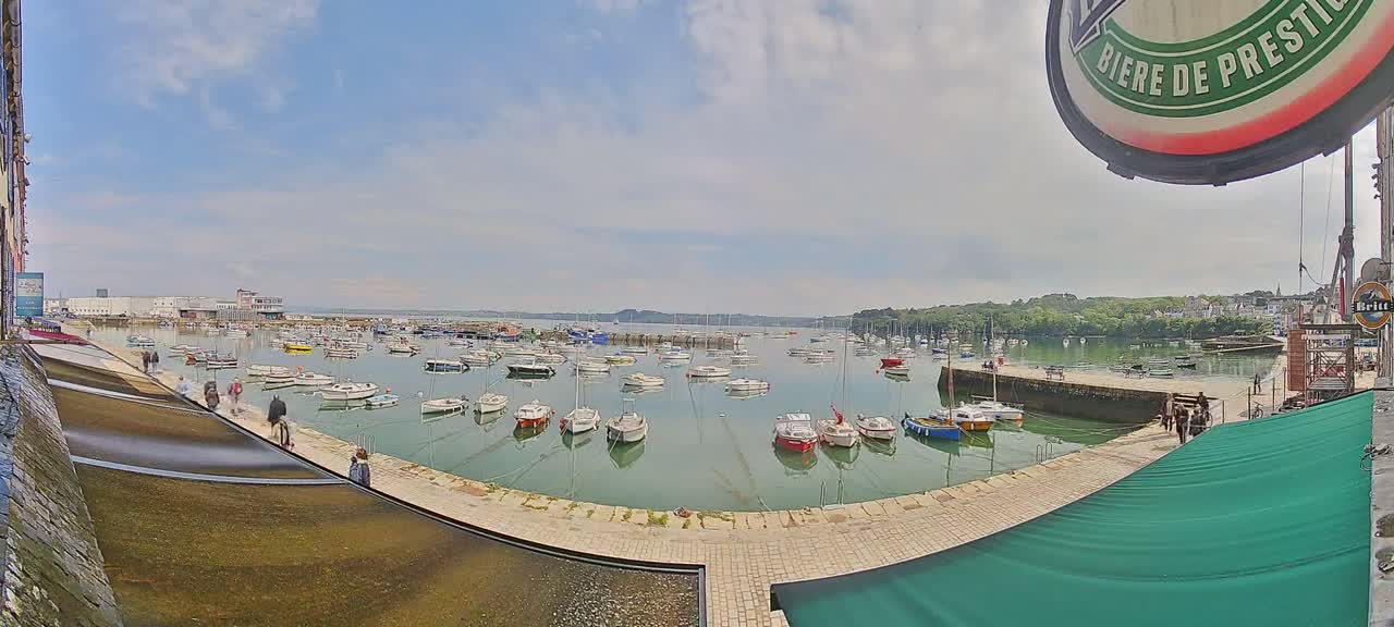 A harbor filled with numerous small boats under a partly sunny sky.