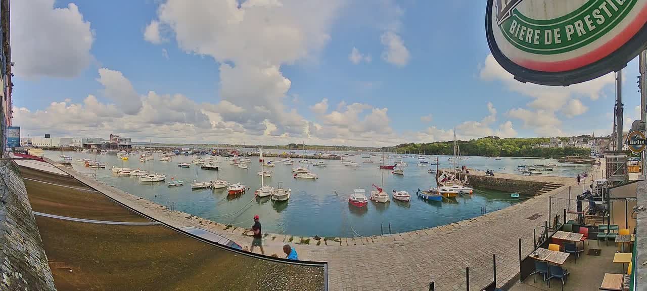 A harbor filled with numerous small boats under a partly cloudy sky.