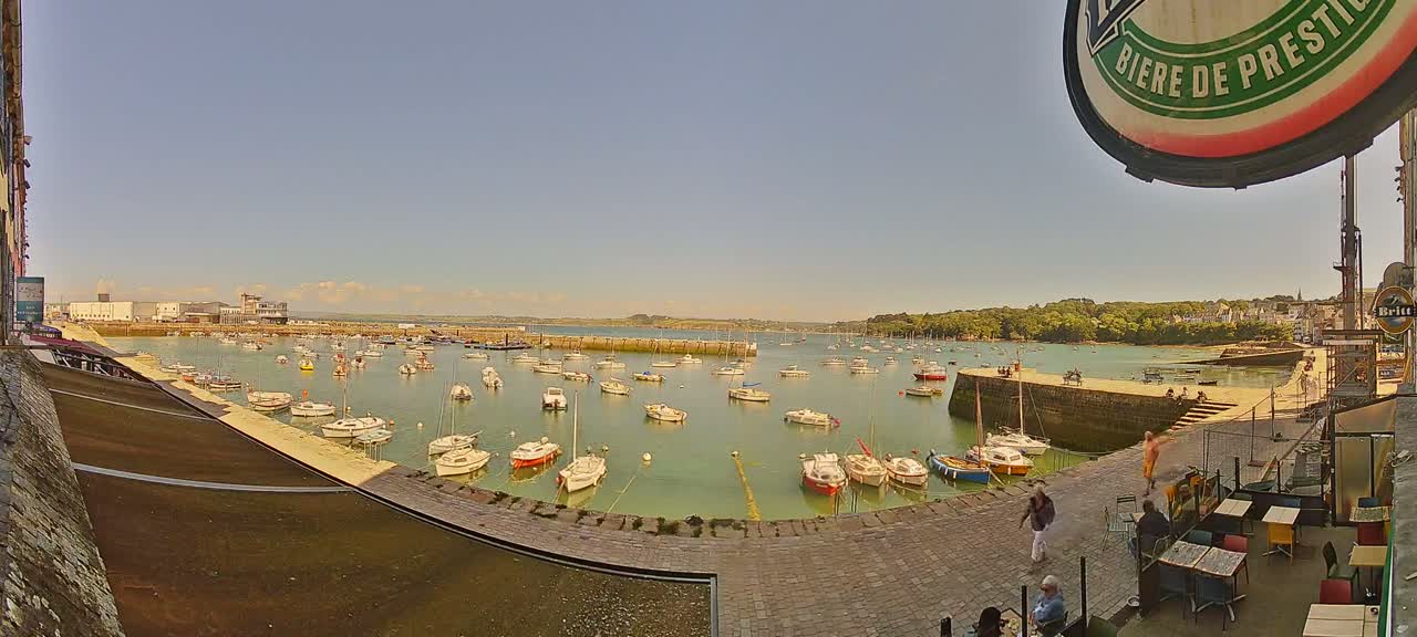A harbor filled with numerous small boats is viewed from a waterfront patio on a sunny day.