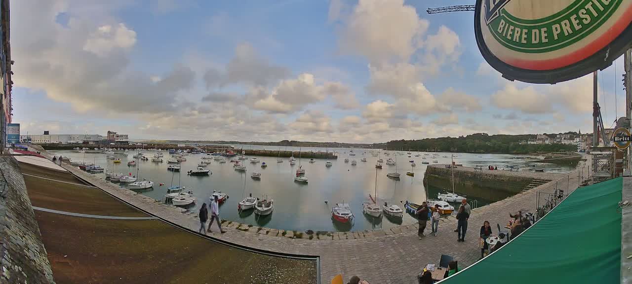A harbor filled with numerous small boats under a partly cloudy sky.
