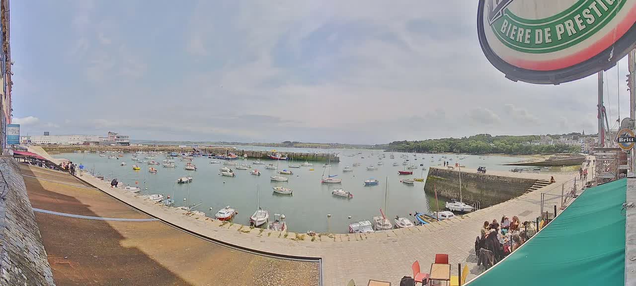 A harbor filled with numerous small boats on a partly cloudy day.
