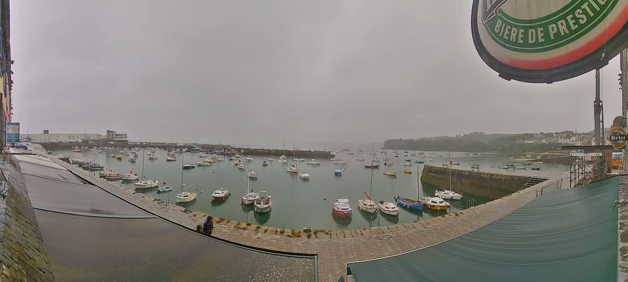 Many boats are moored in a harbor on an overcast day.
