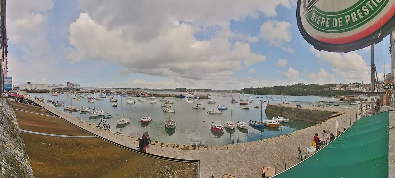 A harbor filled with numerous small boats under a partly cloudy sky.