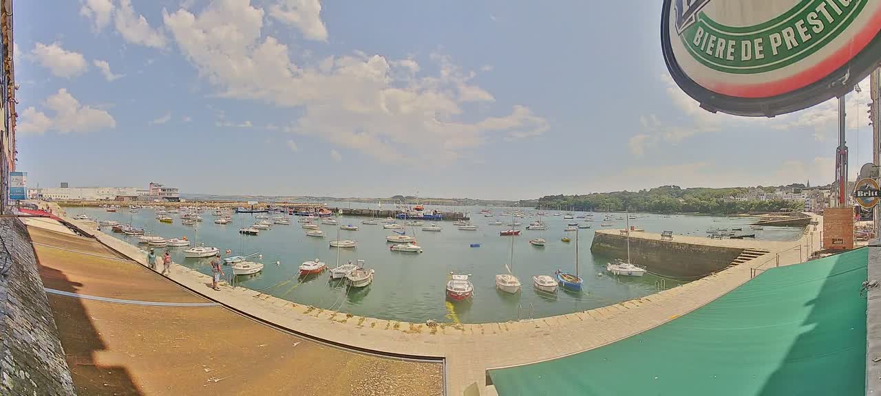 A harbor filled with numerous sailboats and motorboats under a partly cloudy sky.