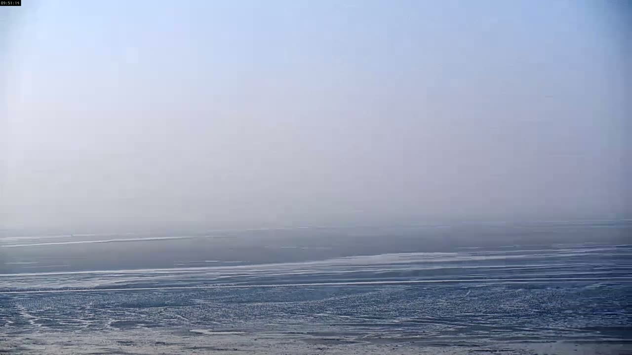 A flat, hazy expanse of water stretches to the horizon under a pale sky.