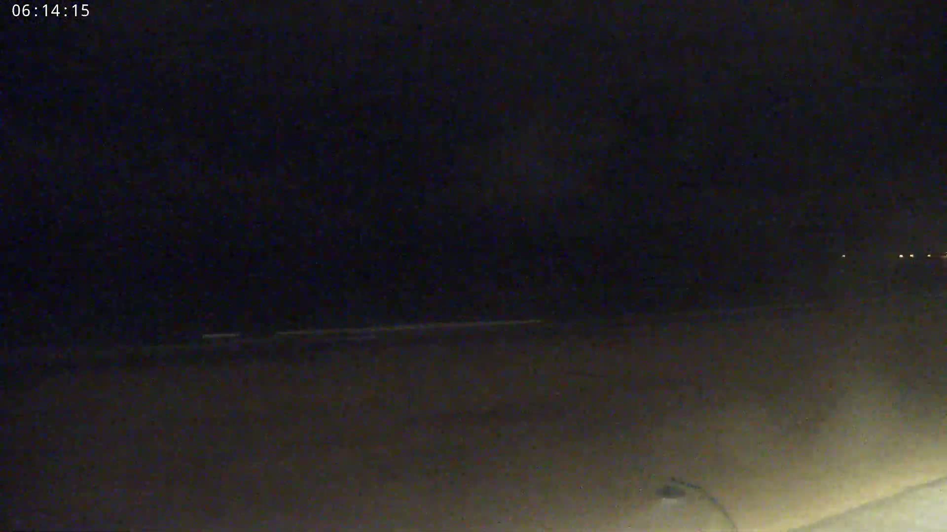 A dark, nighttime beach is visible, with a faint, illuminated horizon line in the distance.
