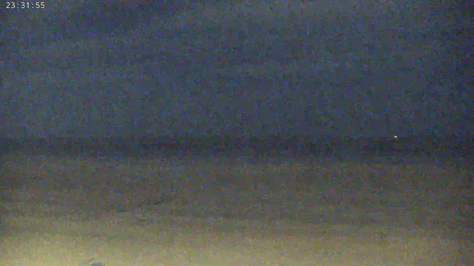 A dark, nighttime beach scene with a dark sky and a faint horizon line.