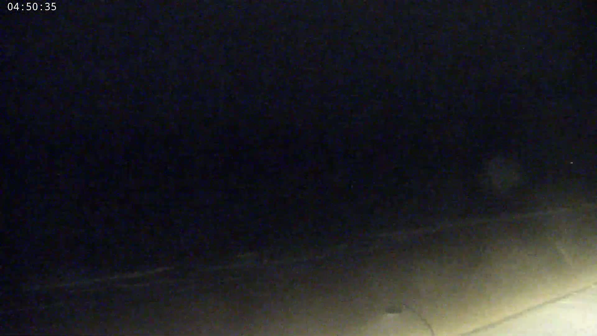 A dark, nighttime scene shows a dimly lit ground with an indistinct horizon under a completely overcast sky.