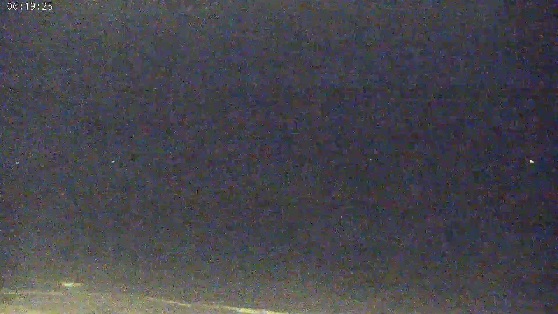 A nighttime, low-light outdoor scene shows a dark expanse with a few distant lights visible.