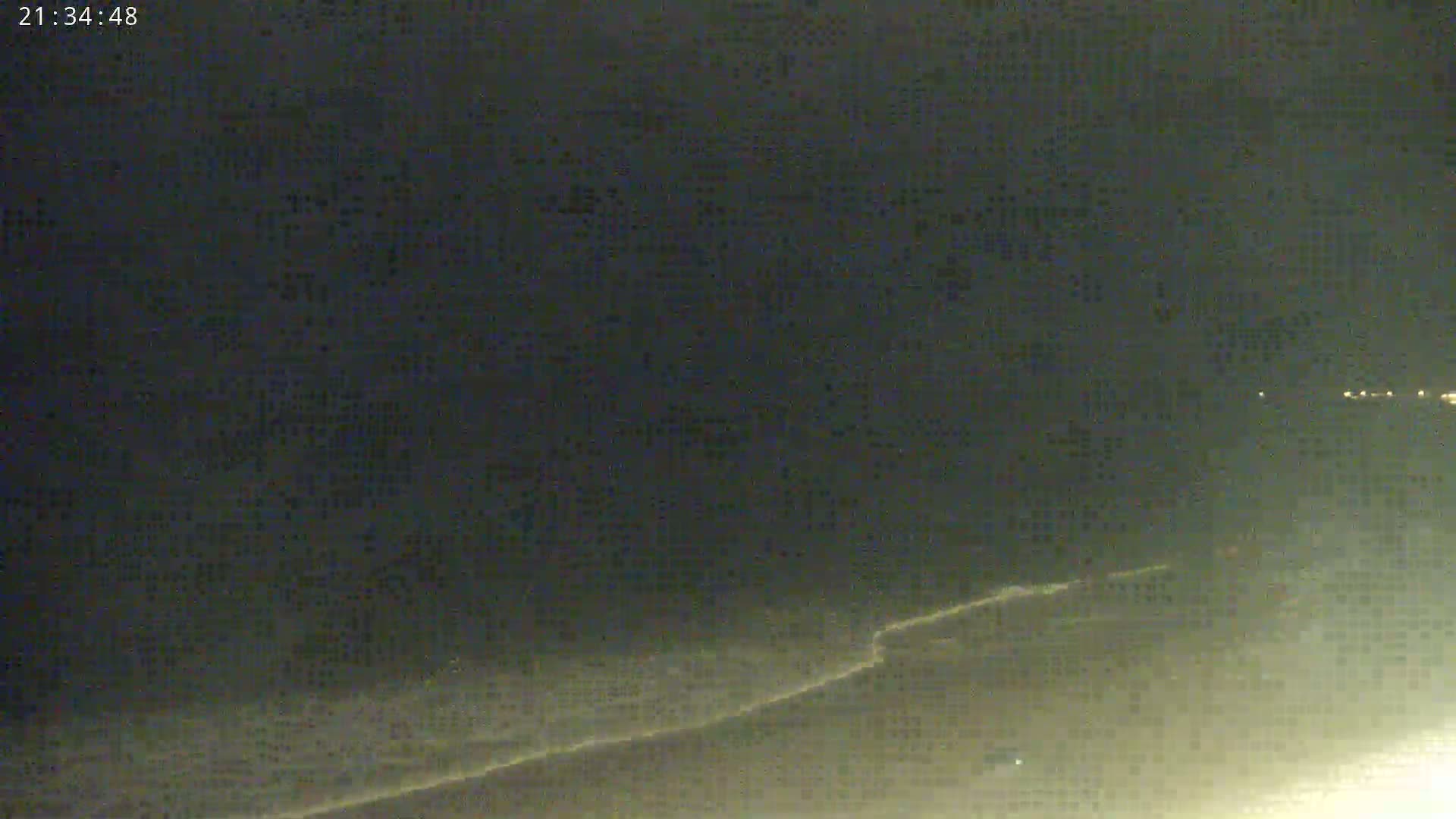 A nighttime, low-light view of a dark beach with gently lapping waves.