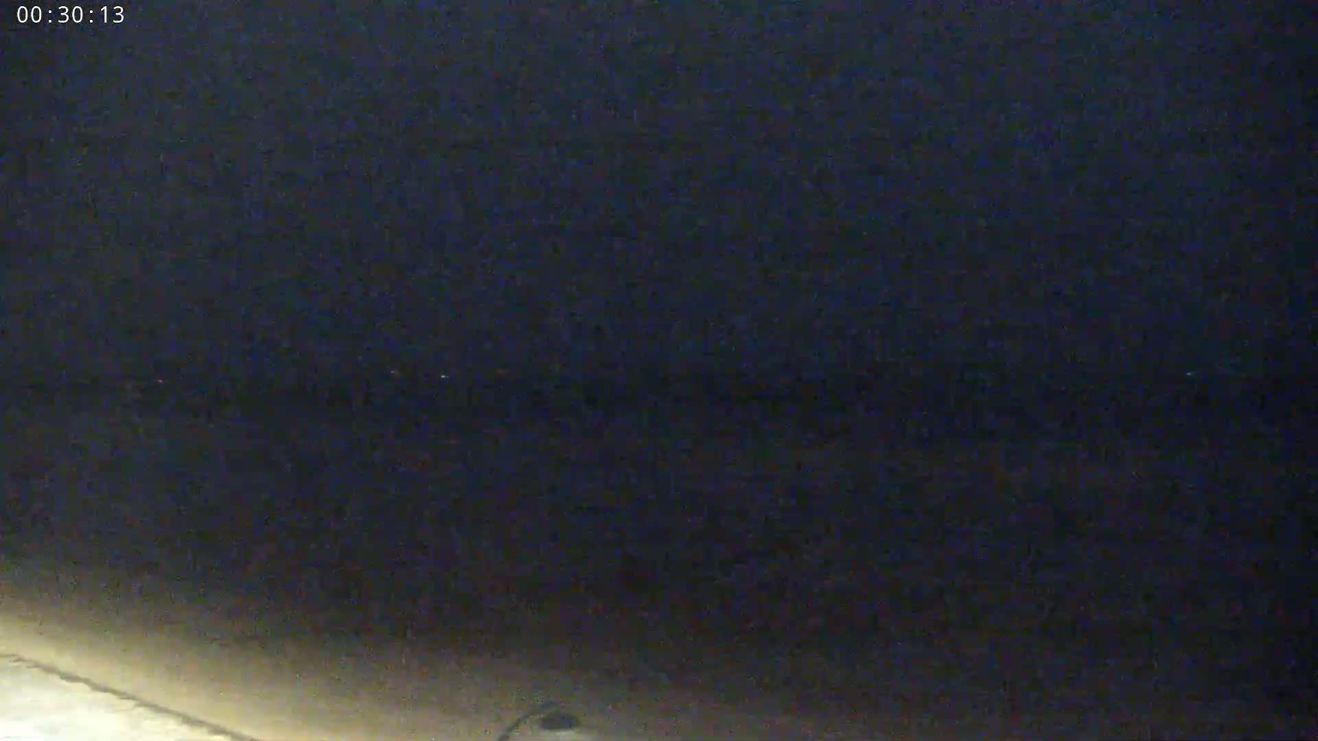 A dark, nighttime scene shows a dimly lit ground with a dark sky above.