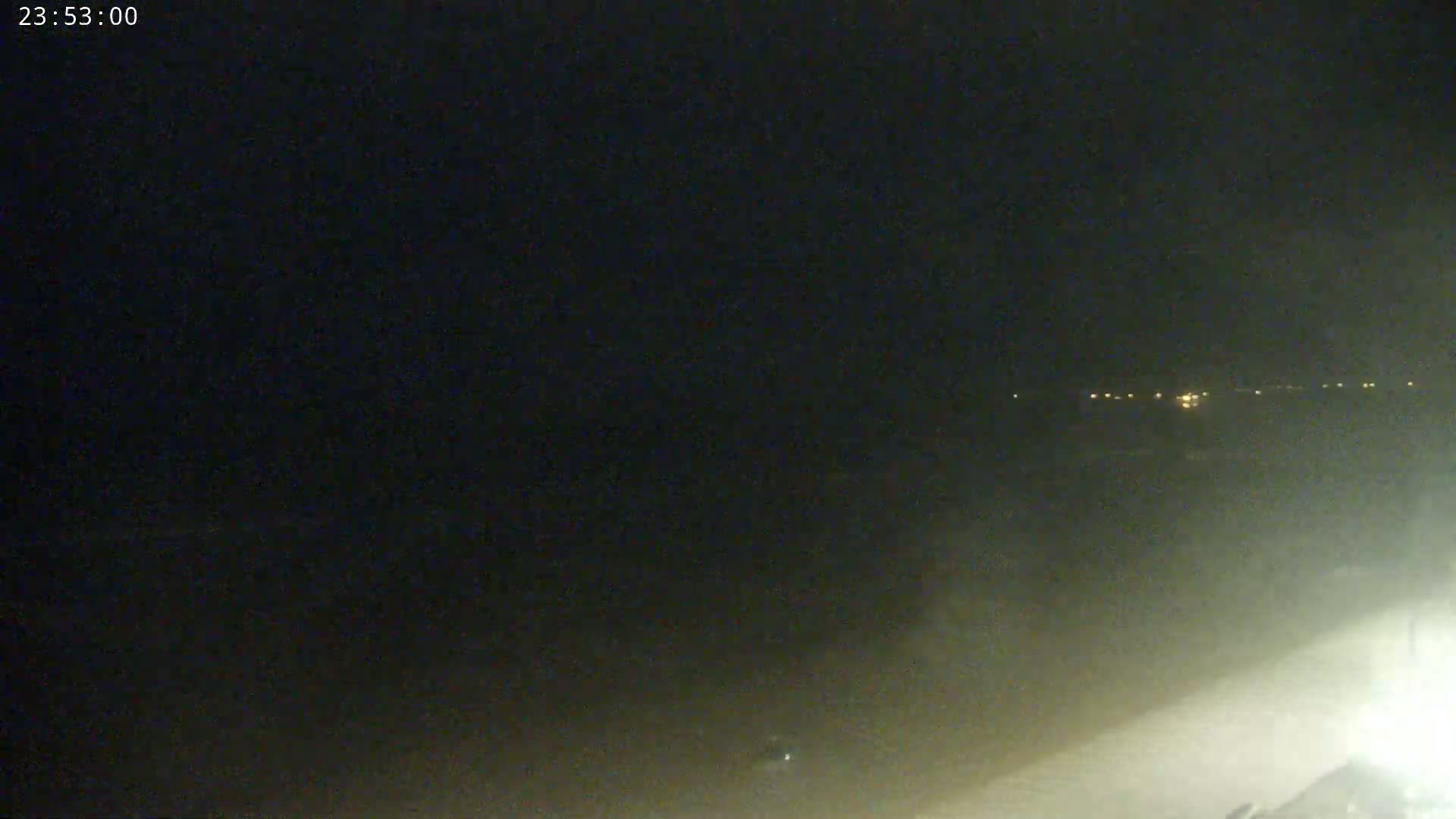 A nighttime, hazy, outdoor scene shows a distant line of faint lights on the horizon.