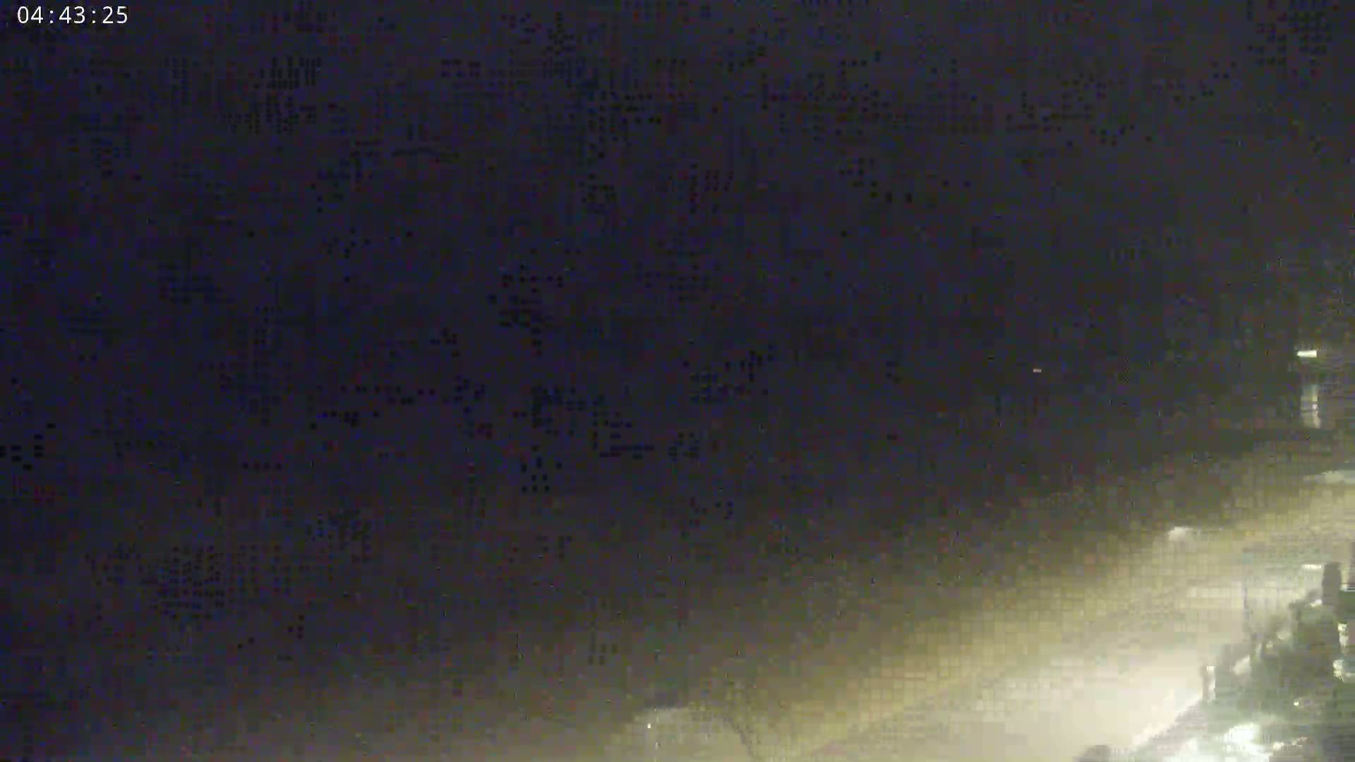 A nighttime, hazy or foggy scene shows indistinct shapes and lights in the lower right corner.