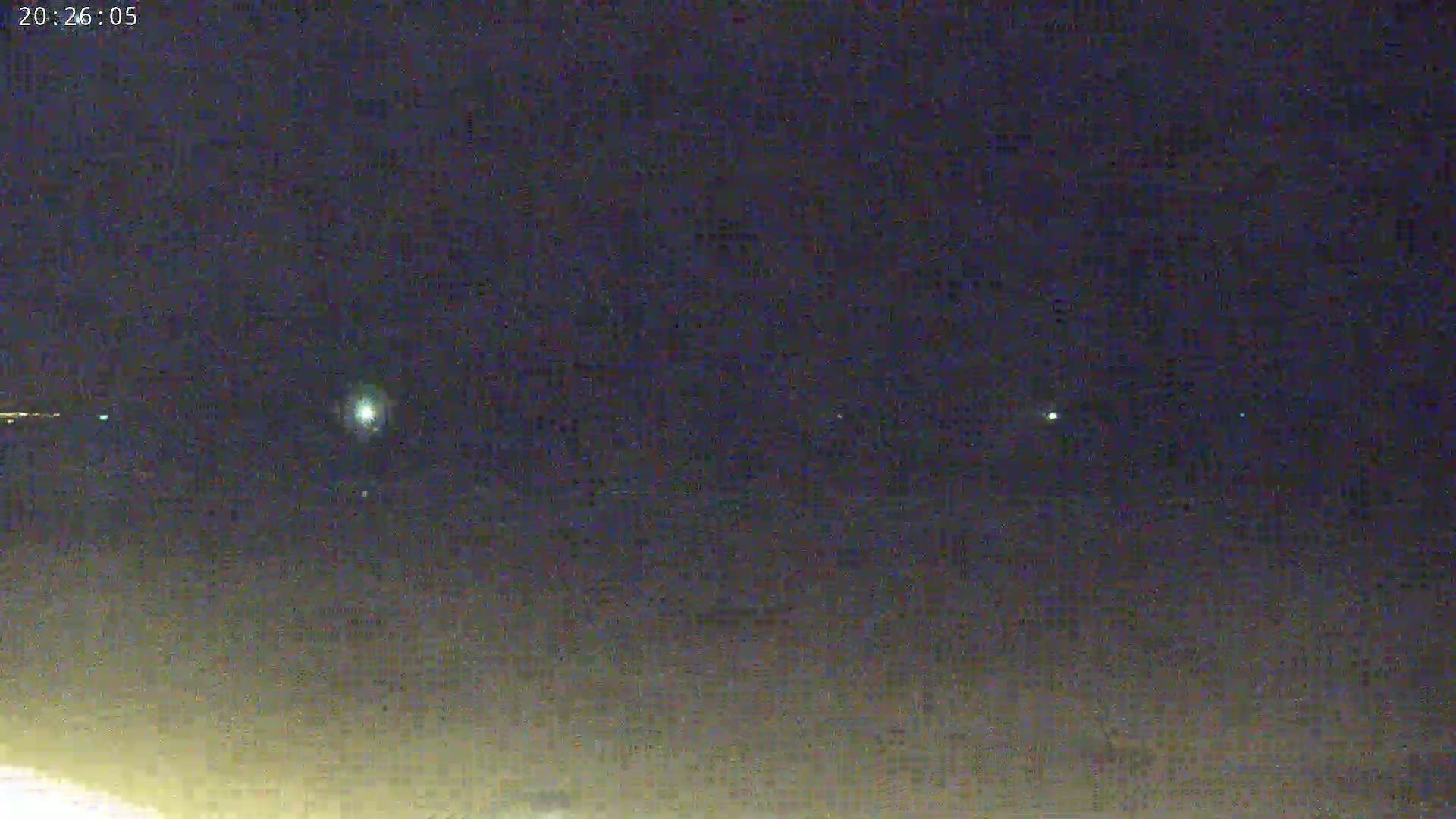 A night scene shows several faint lights in the dark sky above a dimly lit ground.