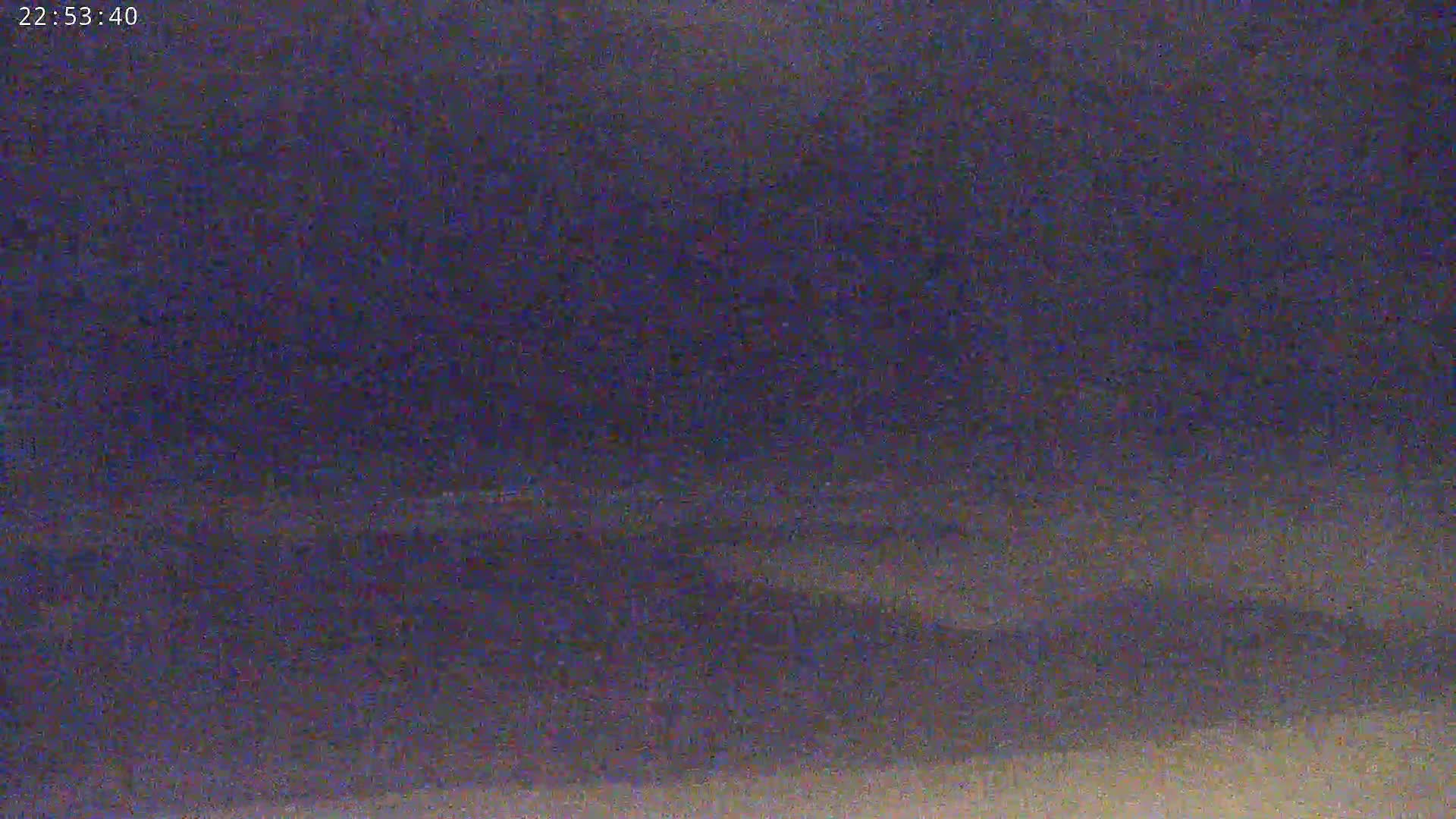 A nighttime, blurry image shows a dark sky and indistinct land.