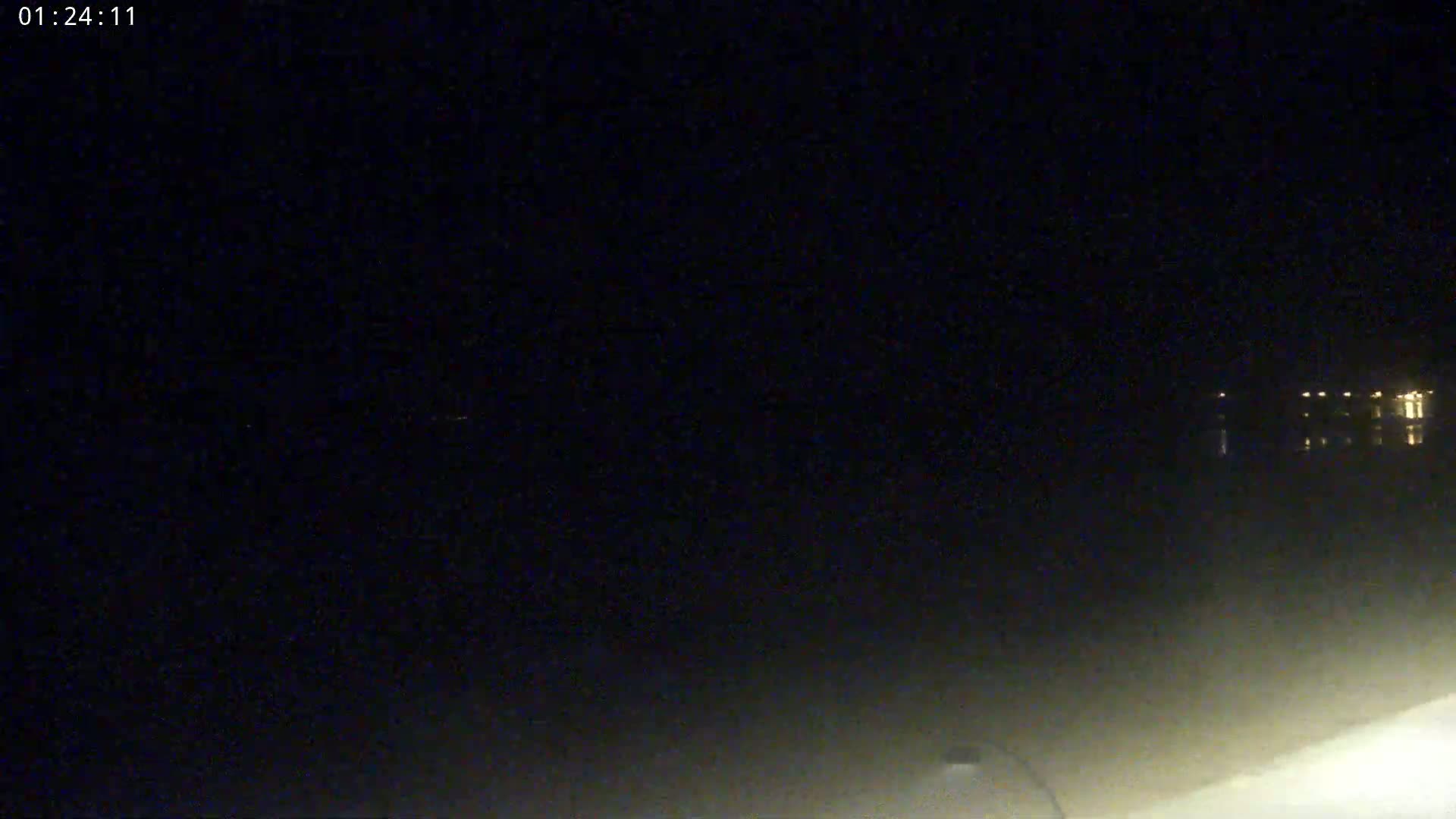 A nighttime, low-light view of a dark body of water with faintly visible lights in the distance.