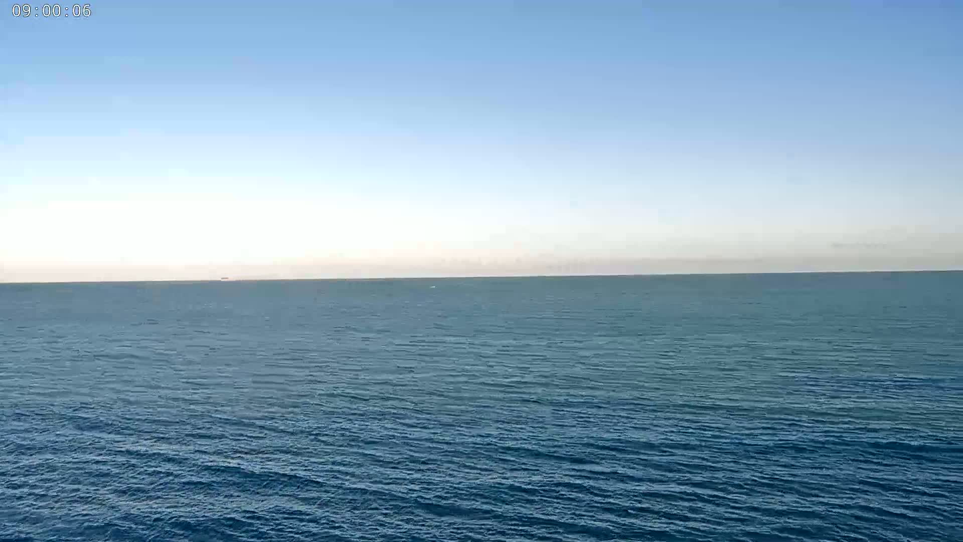 A calm, blue ocean stretches to the horizon under a clear, light blue sky.