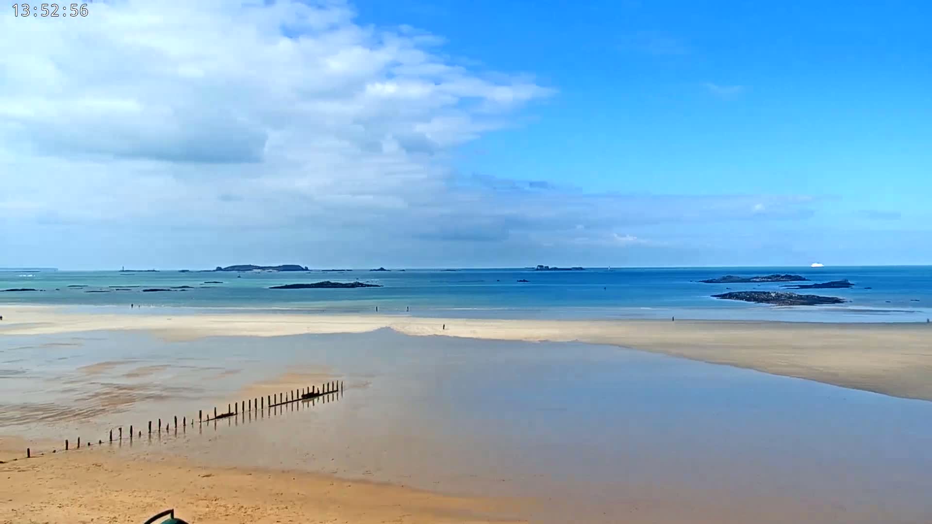 A sandy beach stretches out to a calm, blue ocean under a partly cloudy sky.