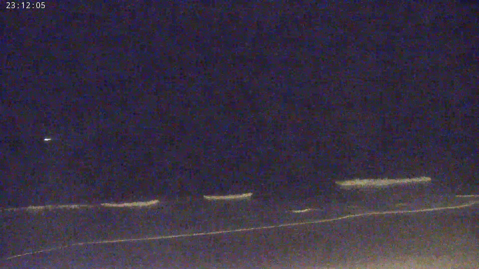 A nighttime, low-light view of a dark body of water with faint white lines suggesting waves or reflections.