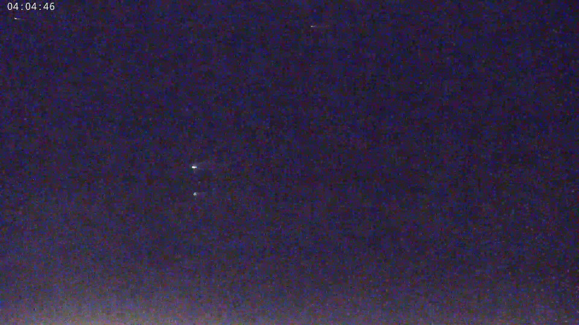 A nighttime outdoor scene shows a dark blue sky with several faint, distant lights.