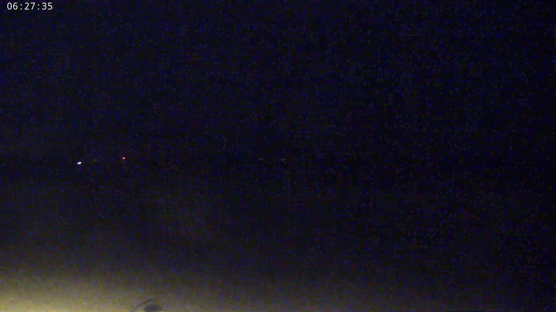 A nighttime long shot shows a dark sky with a few distant lights visible on the horizon.