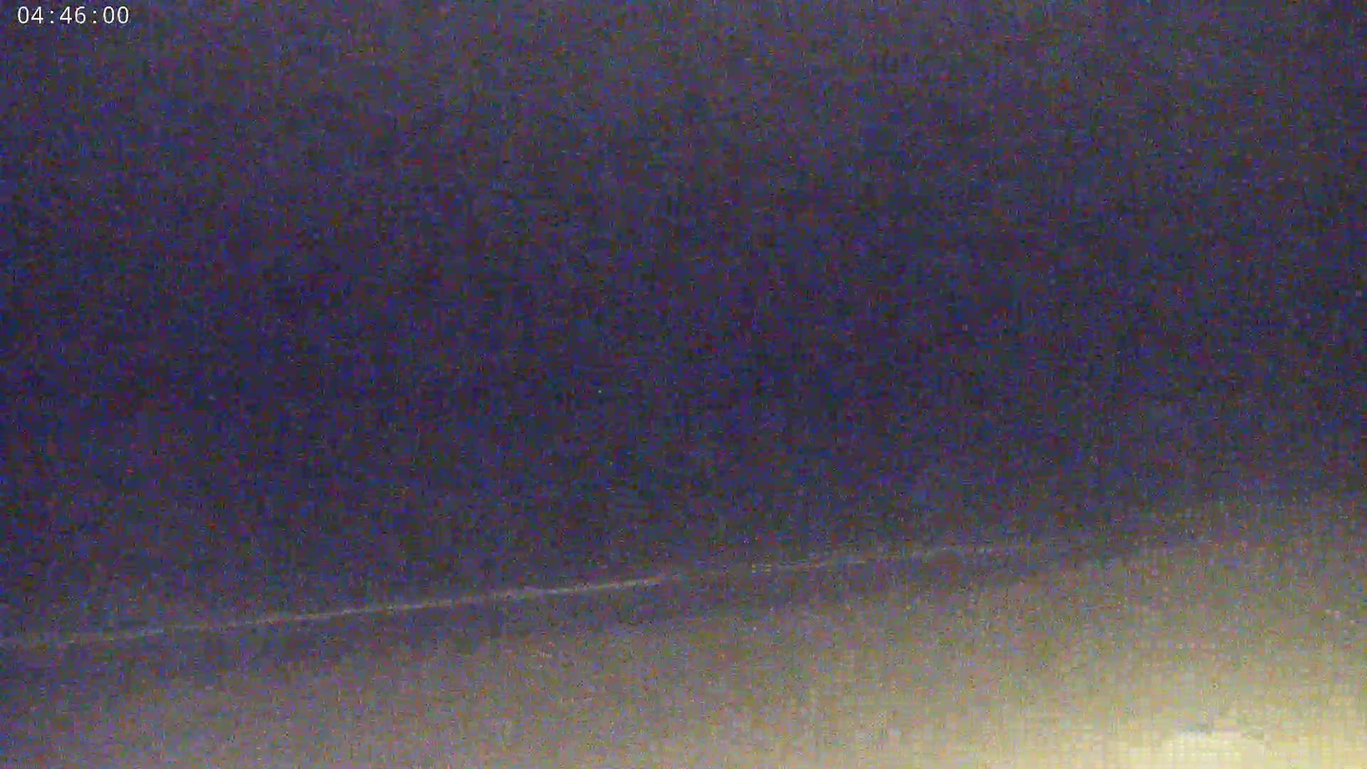 A low-light, nighttime image shows a dark, possibly overcast sky with a faint horizontal line near the bottom.