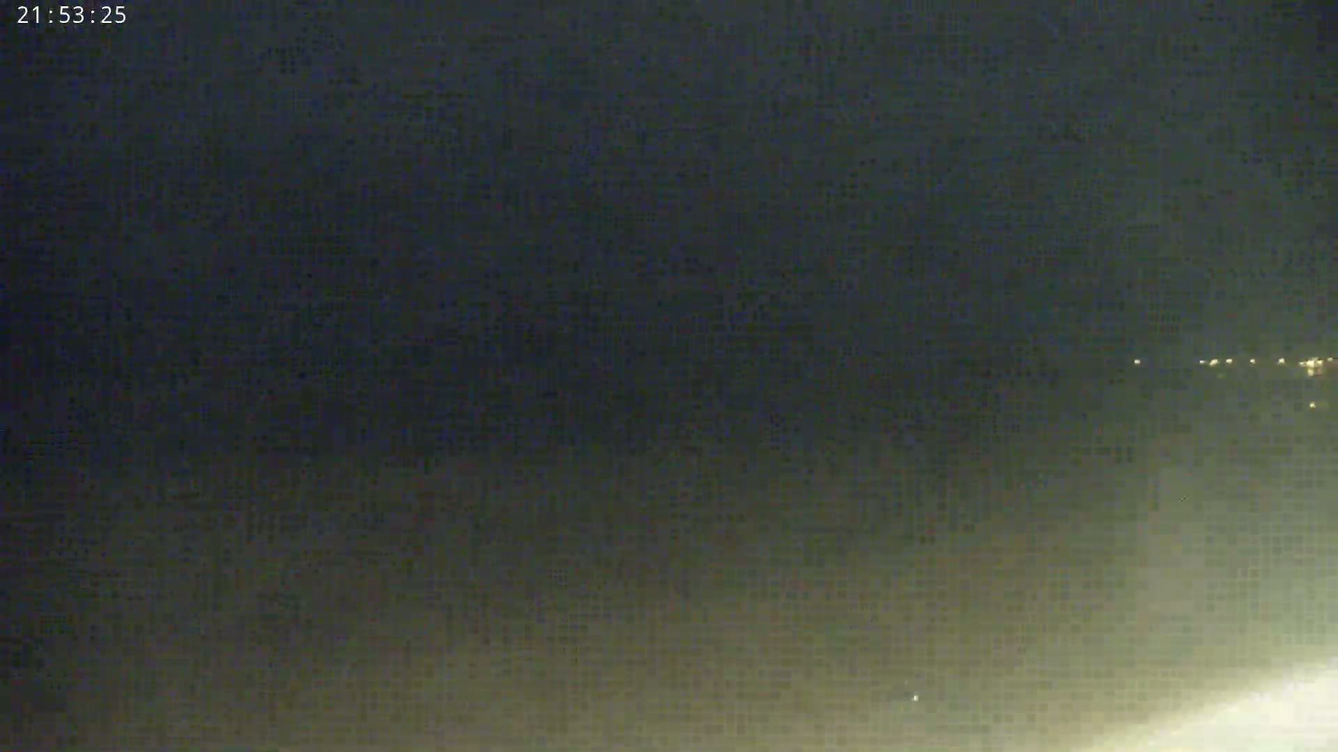 A nighttime, hazy view shows a distant line of lights on the horizon.