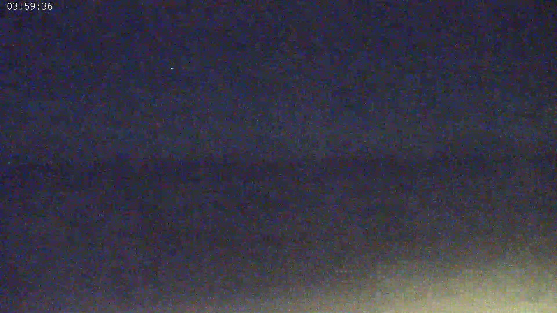 A nighttime outdoor scene shows a dark, possibly cloudy sky with a faint light horizon.