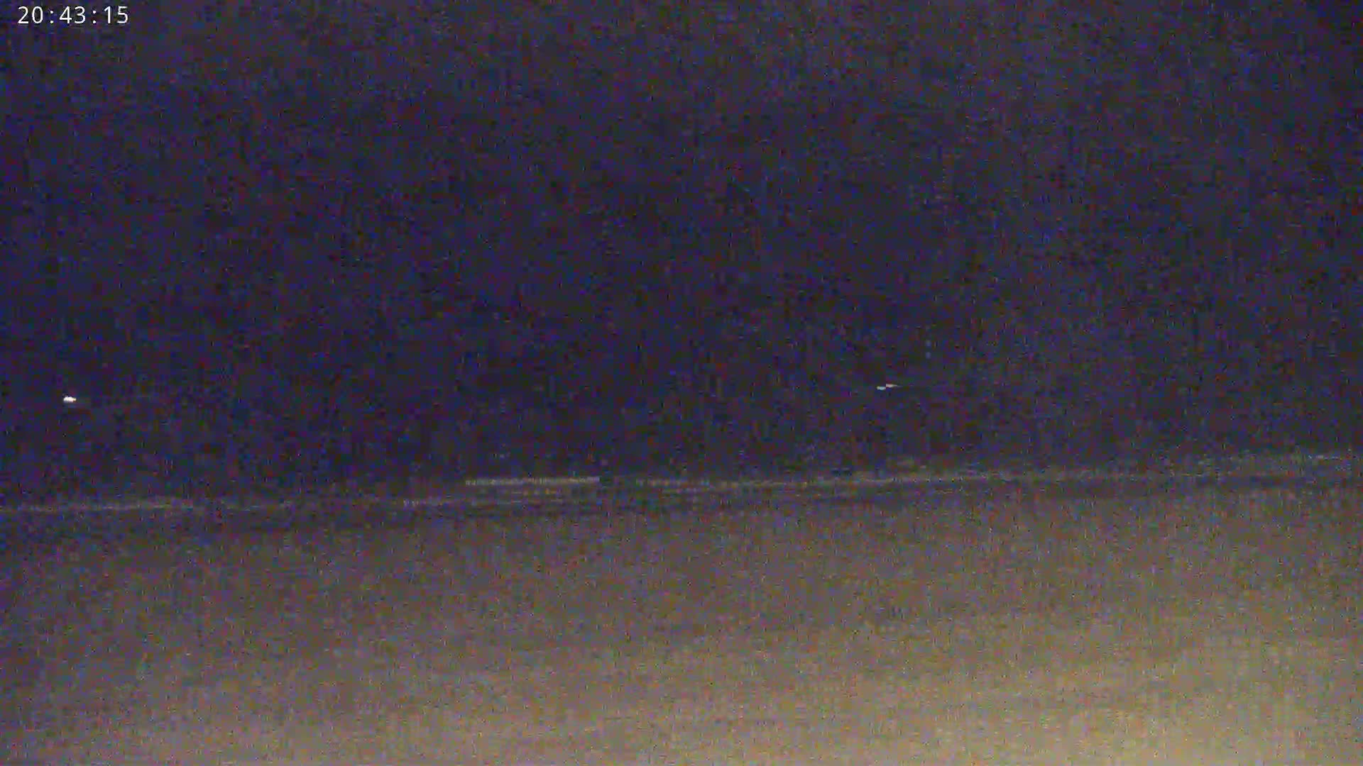 A dark, nighttime beach scene is visible under a mostly clear, dark sky.