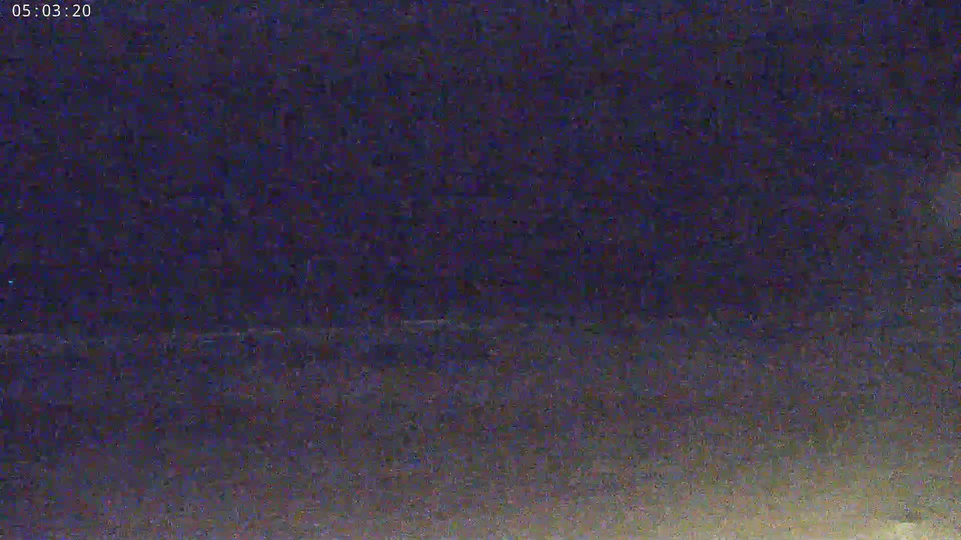A dark, nighttime scene shows a blurry, low-light view of an indistinct landscape.