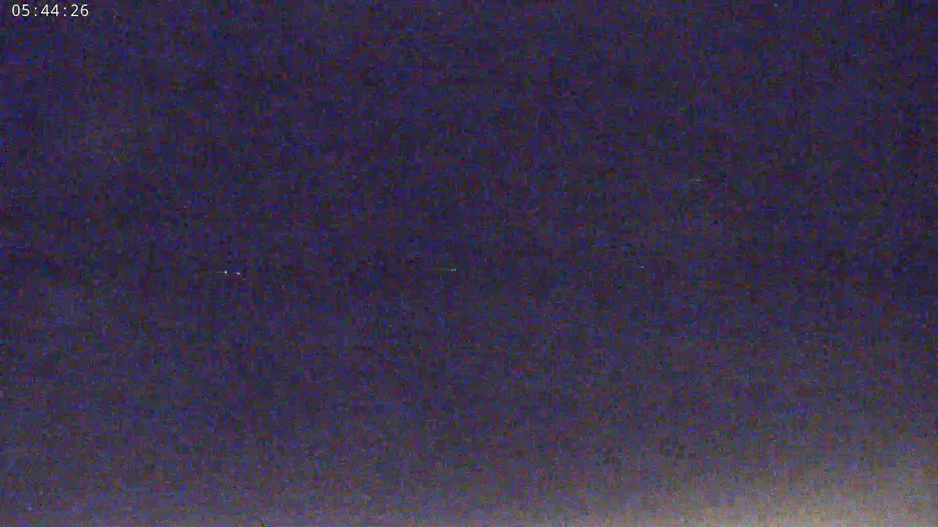 A dark, nighttime sky shows a few faint lights in the distance.