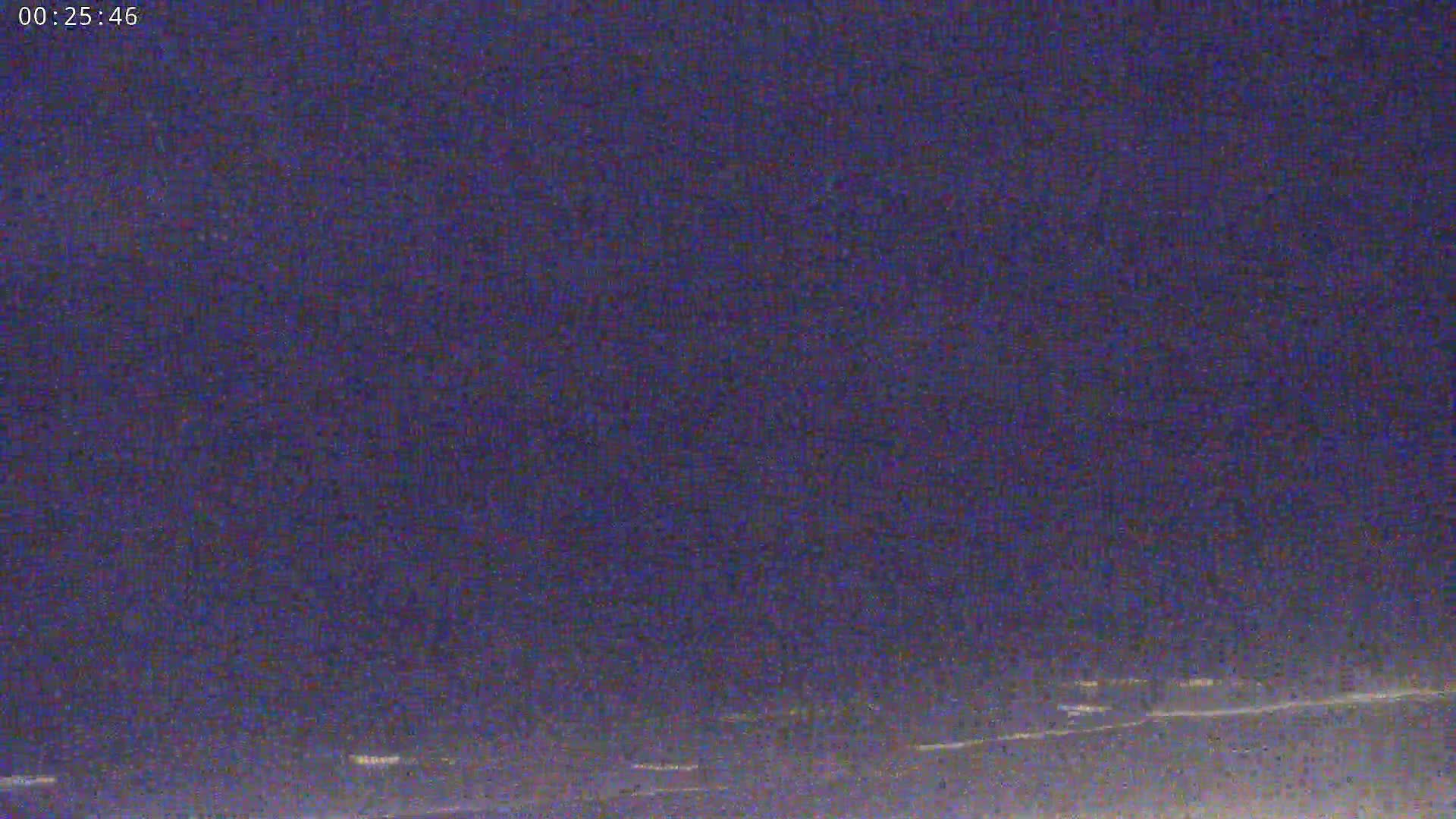 A nighttime long shot shows a dark purplish sky over a dimly lit horizon.