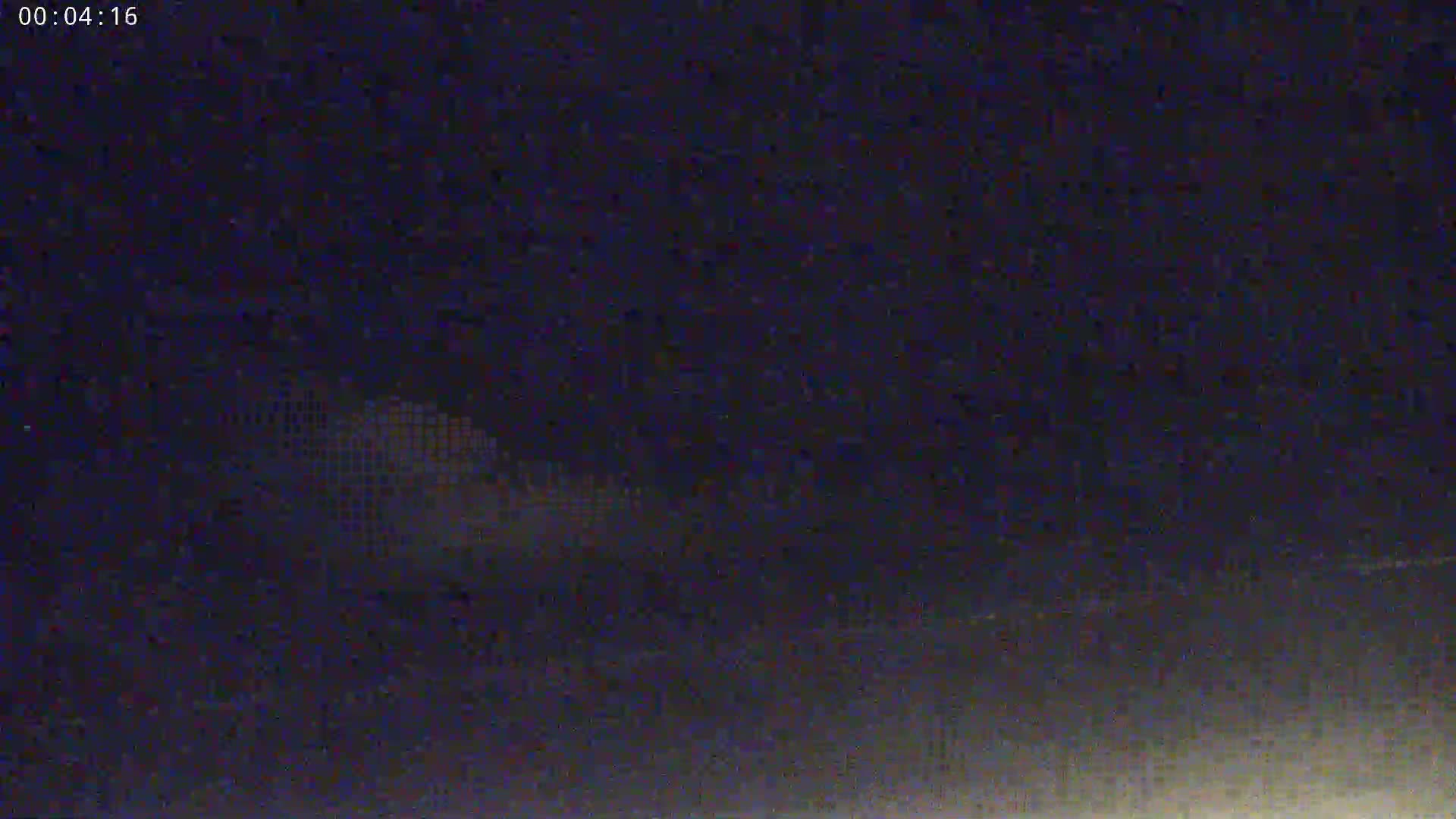 A low-resolution nighttime image shows a blurry, possibly pixilated, object in the distance against a dark sky.