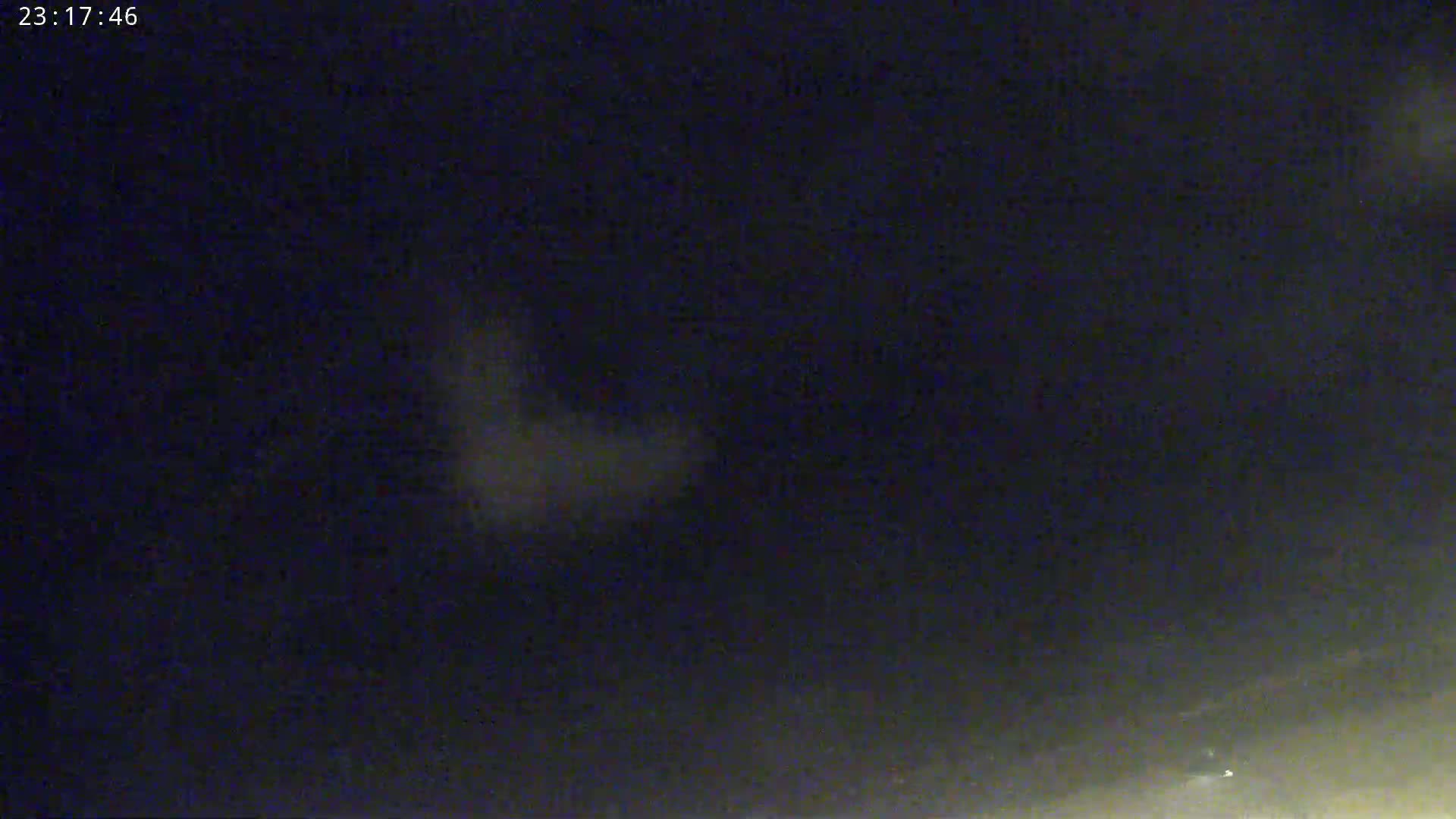 A blurry, light-grey shape resembling a sideways “L” is visible against a dark, nighttime sky.