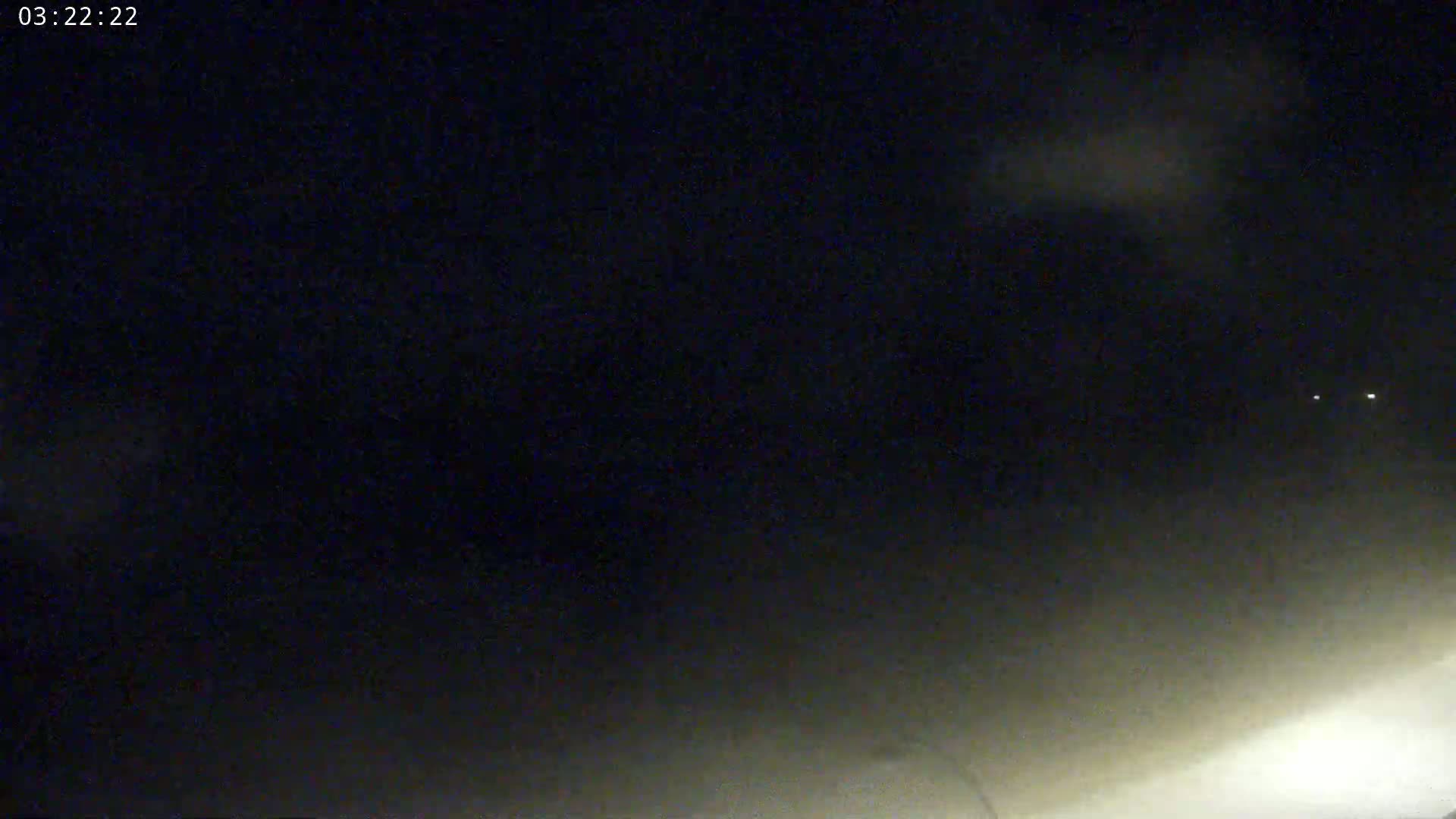 A nighttime outdoor scene shows a dark sky with a few faint clouds and distant lights.