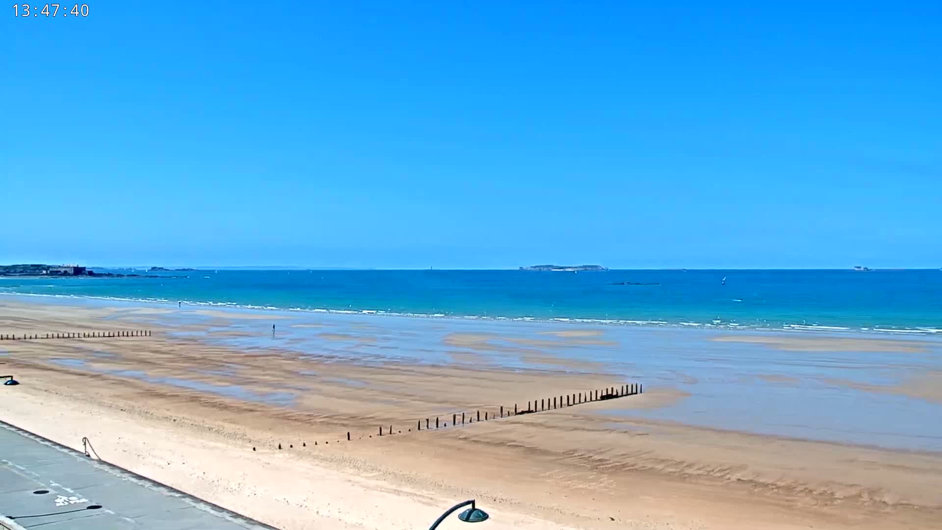 A sandy beach stretches to a calm, turquoise ocean under a clear blue sky.