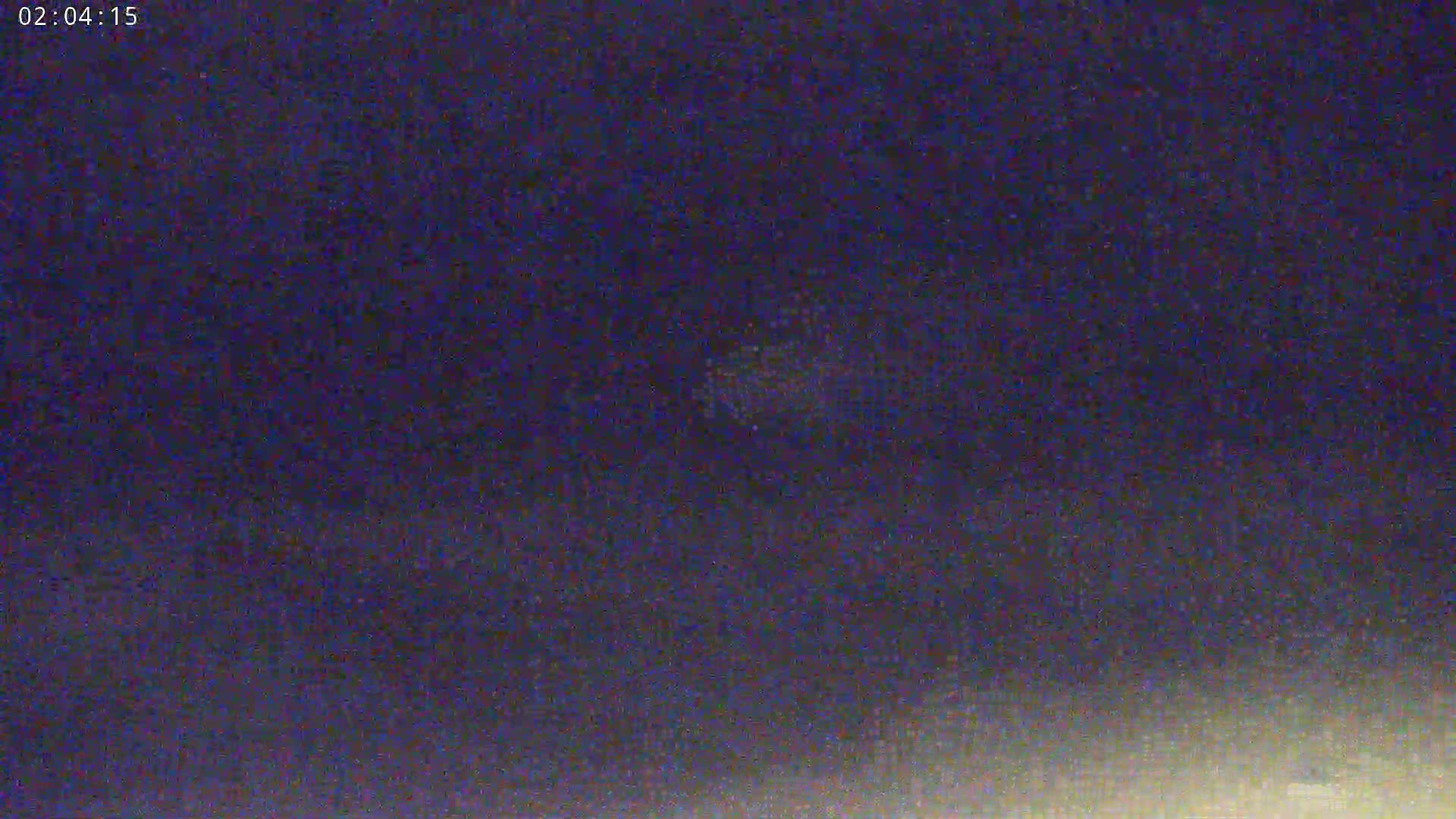 A low-light, grainy image shows a dark night sky.