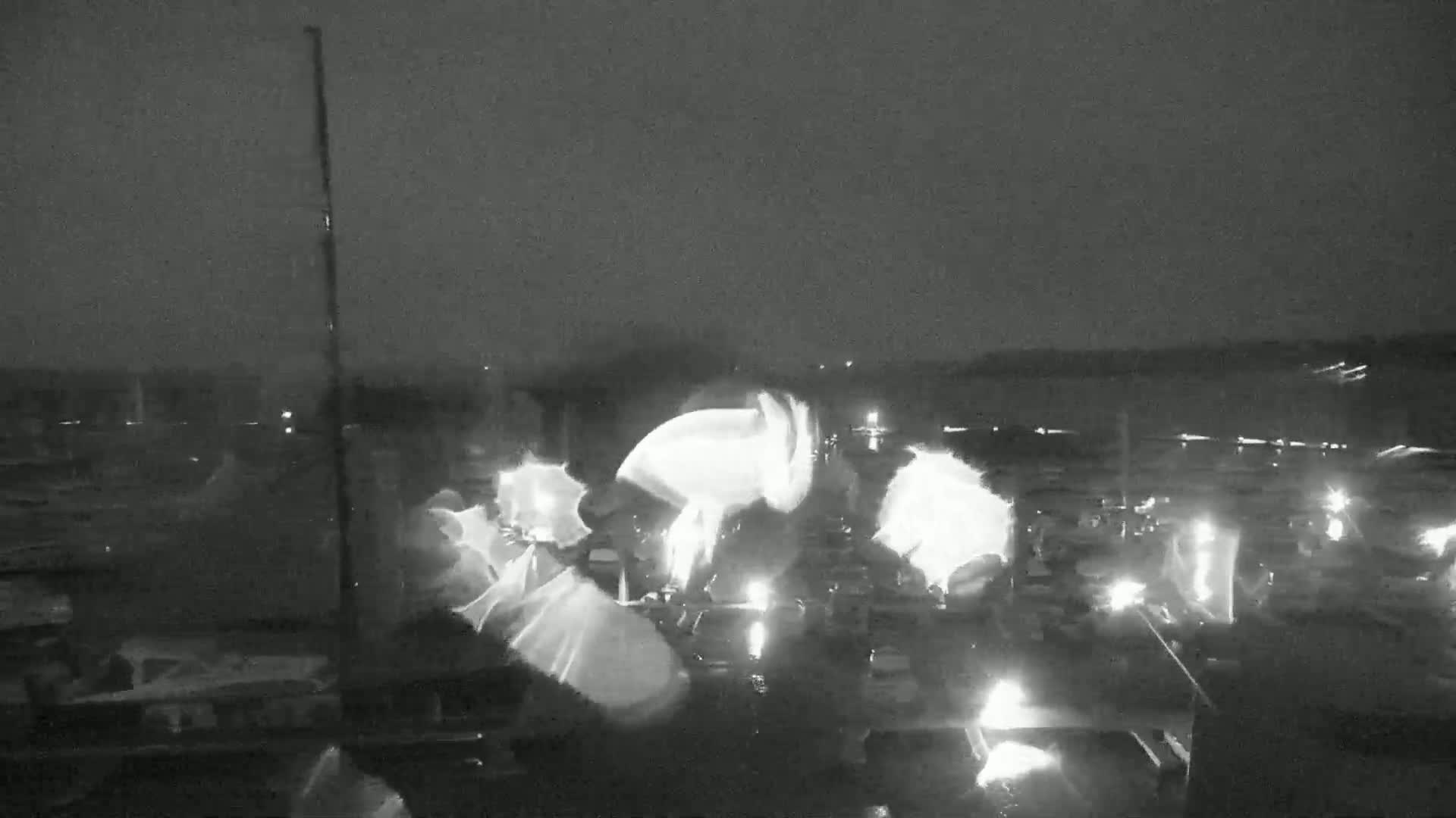 A nighttime, low-light image shows a marina at night with several boats illuminated by small lights.