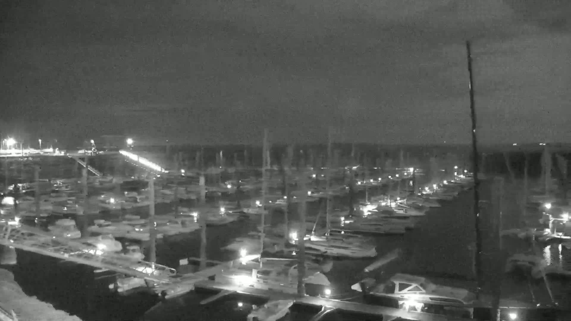 A nighttime, low-light view of a marina filled with numerous boats docked at their slips.