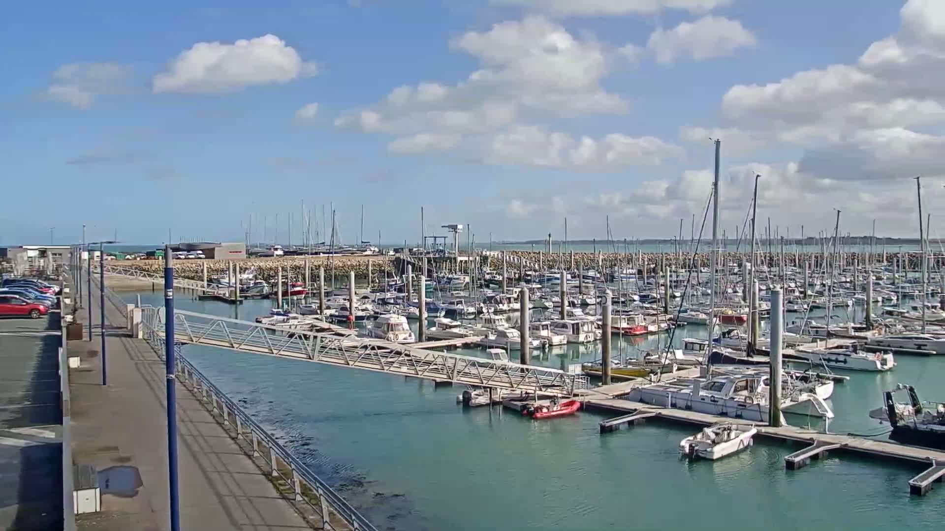 A marina filled with numerous boats and sailboats under a partly cloudy sky.