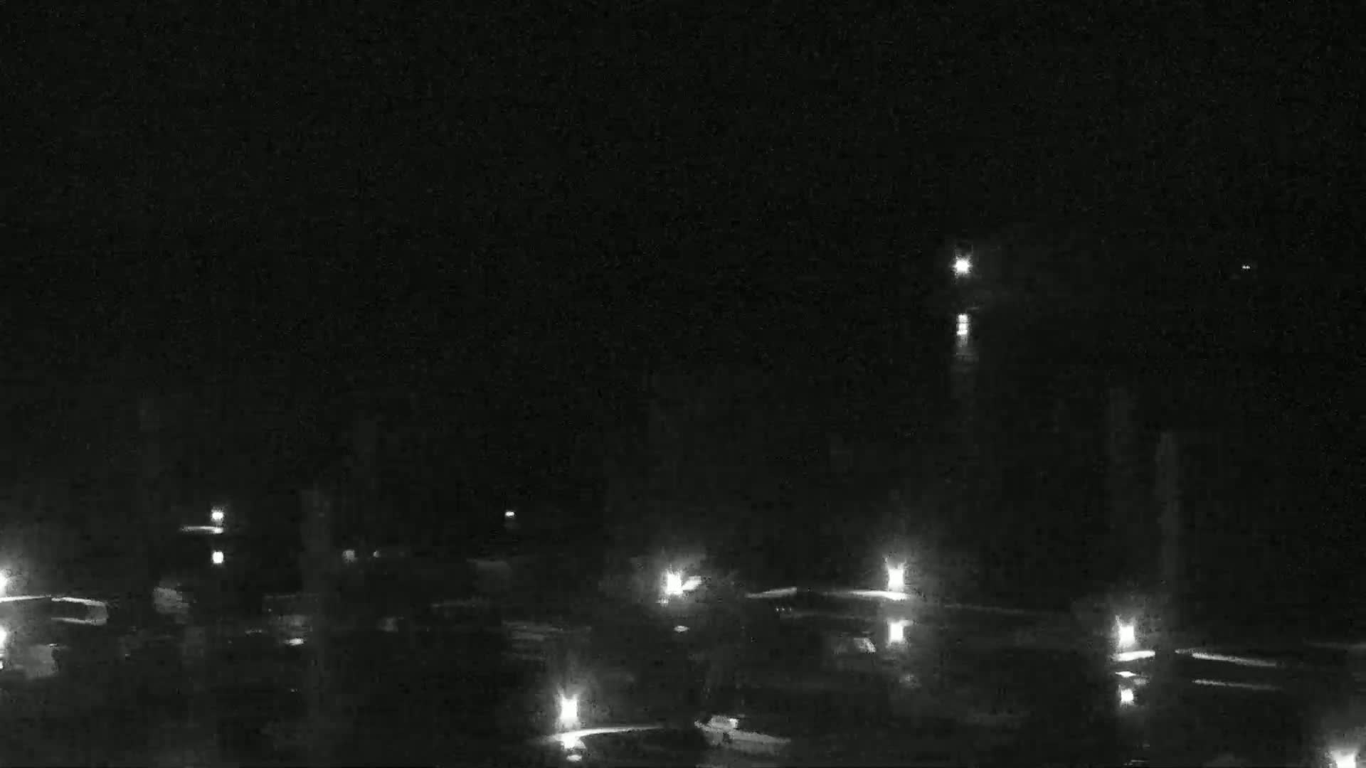 A nighttime view of a dark, possibly watery area with numerous small lights scattered across the surface.