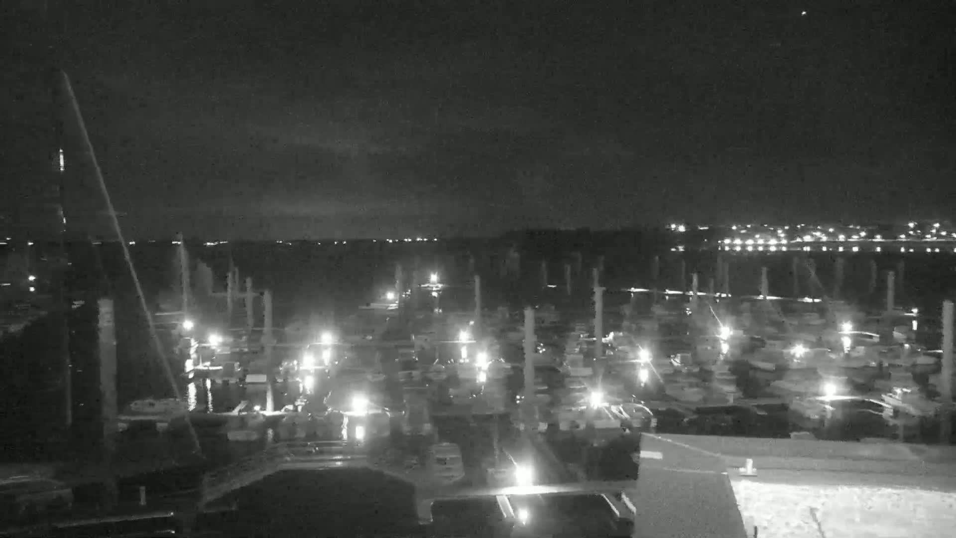 A nighttime, low-light view of a marina filled with numerous boats illuminated by their own lights.