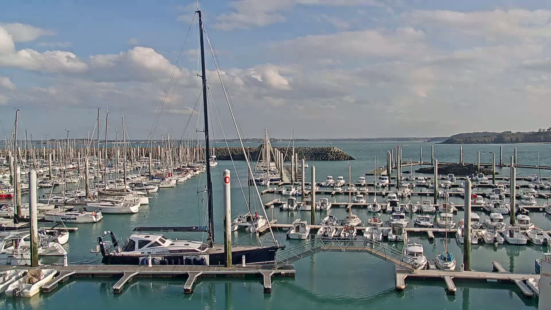 A marina filled with numerous sailboats and motorboats under a partly cloudy sky.