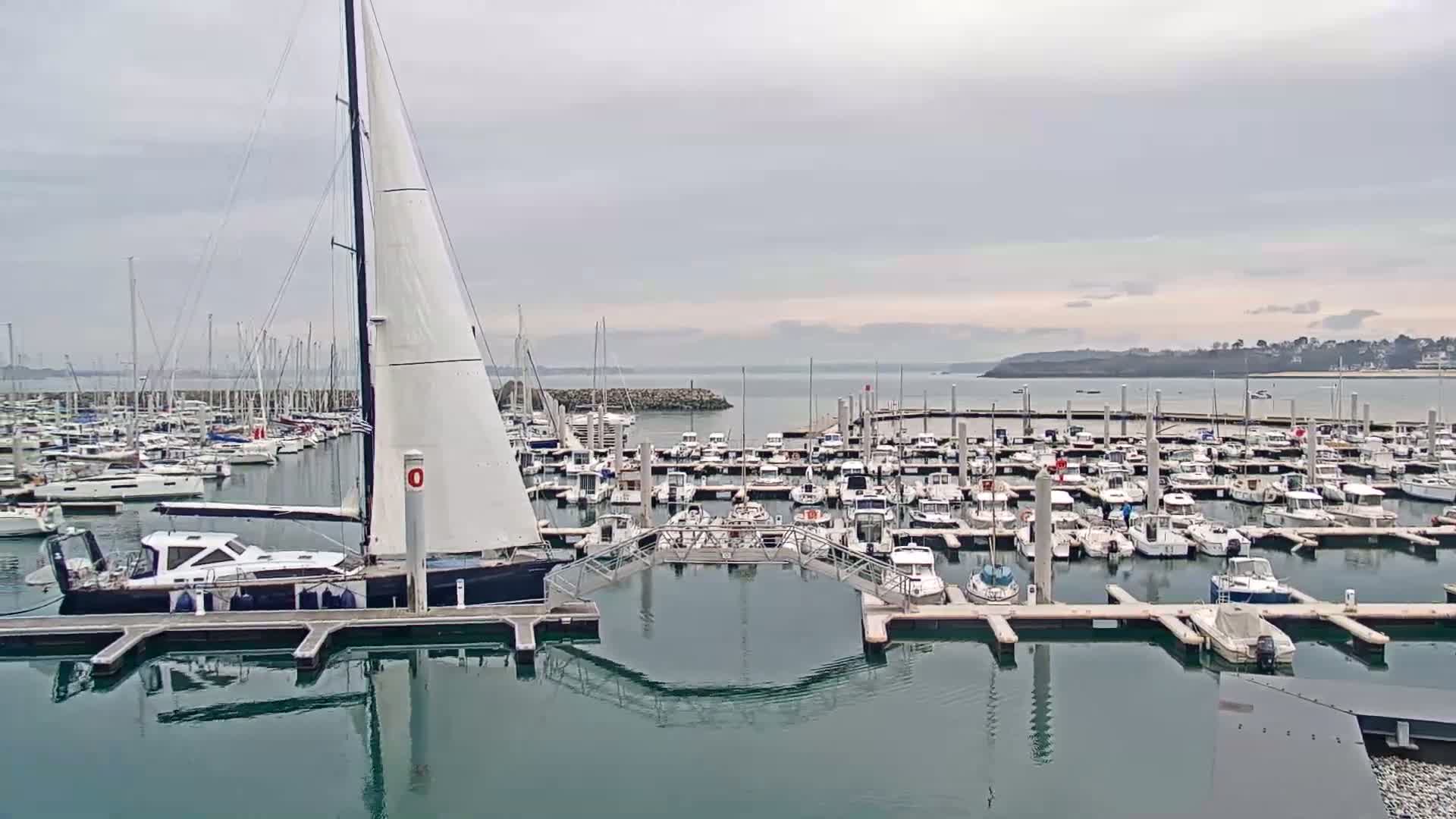 A large marina filled with sailboats and motorboats on a cloudy day.