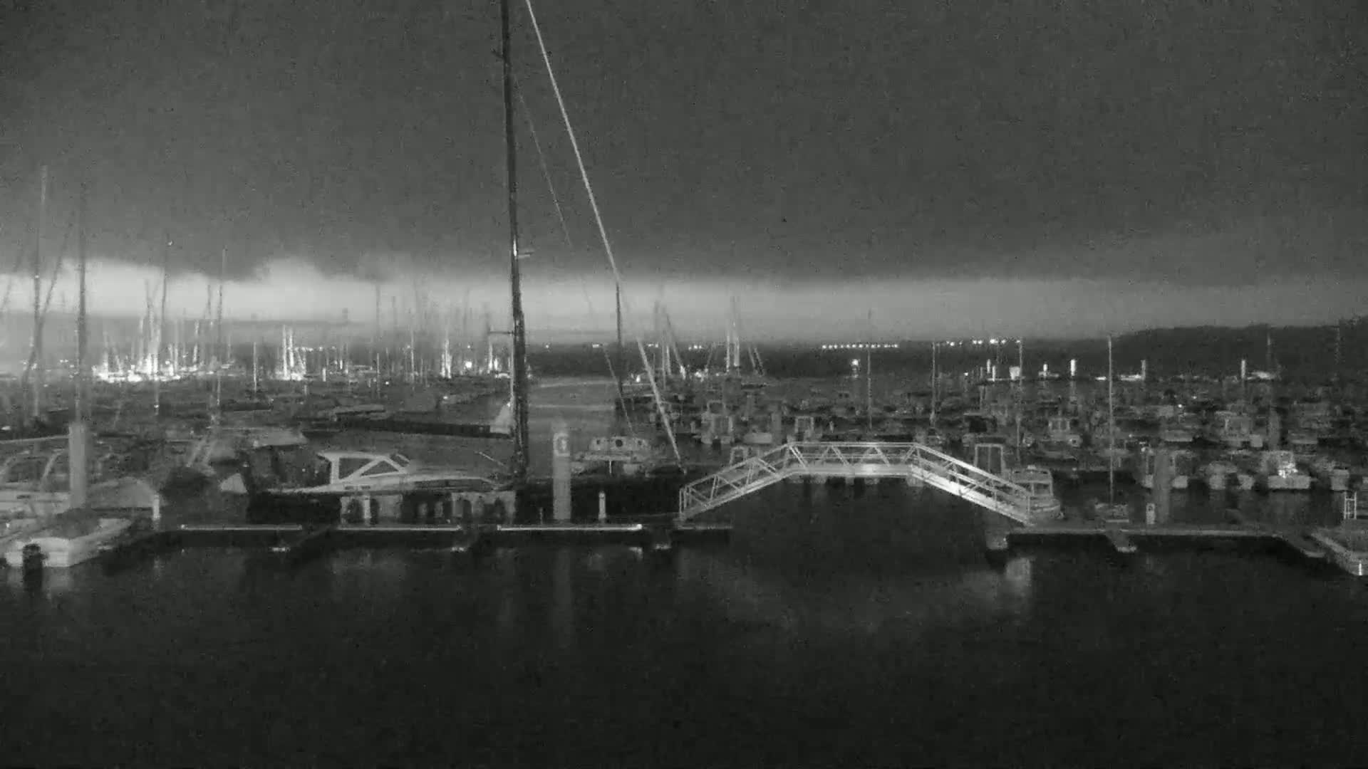 A marina filled with boats at night under a dark, cloudy sky.